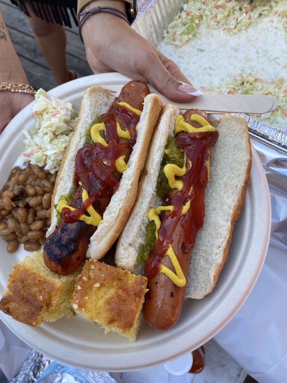 O'Side BBQ Man grilled hot dogs with coleslaw, baked beans, and cornbread